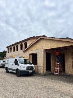 Worker building wooden house exterior near construction van