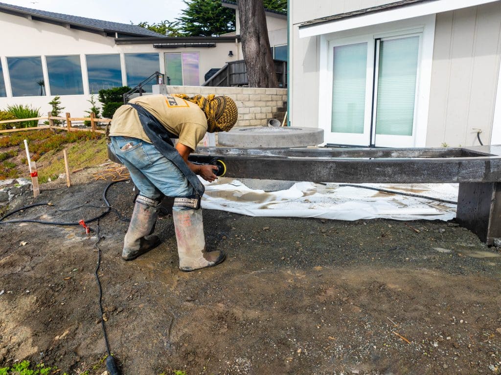 Construction worker sanding concrete beam outdoors