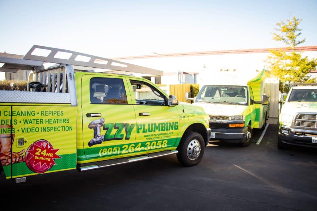 Izzy Plumbing service trucks parked outside building