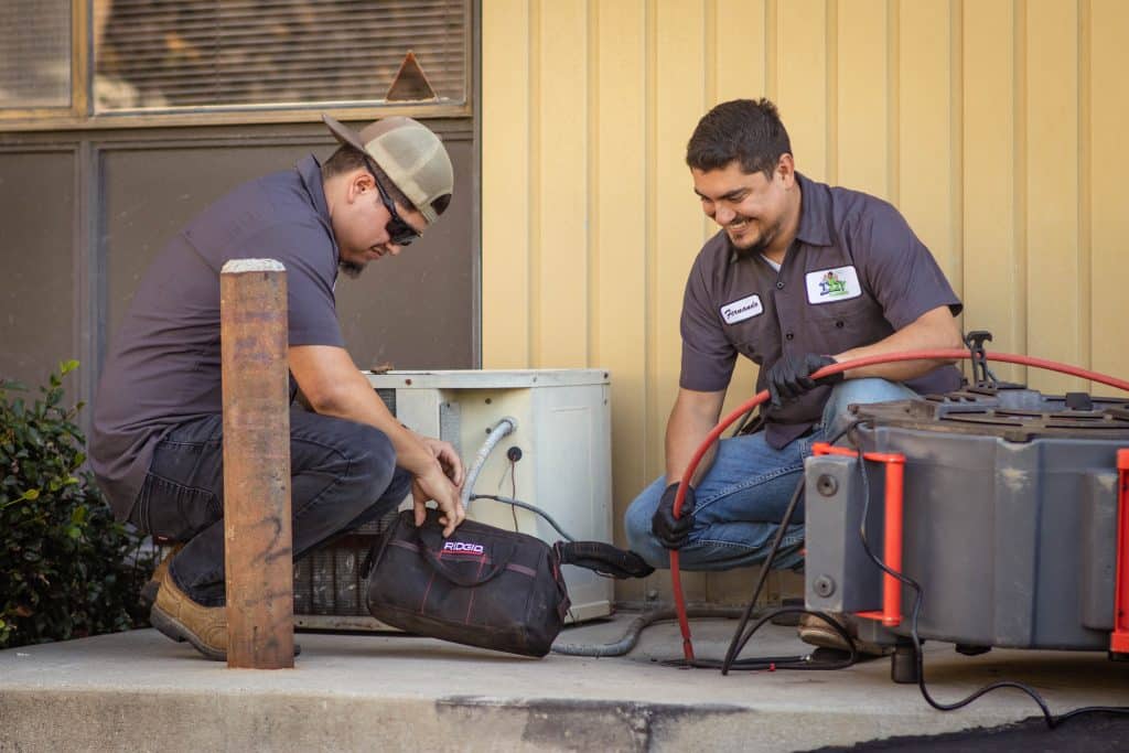 Technicians repairing outdoor air conditioning unit