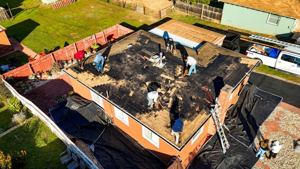 Workers repairing shingles on a house roof
