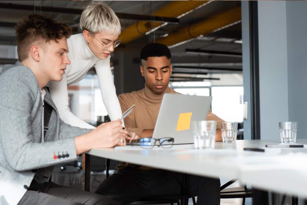 Three colleagues collaborating around laptop in modern office