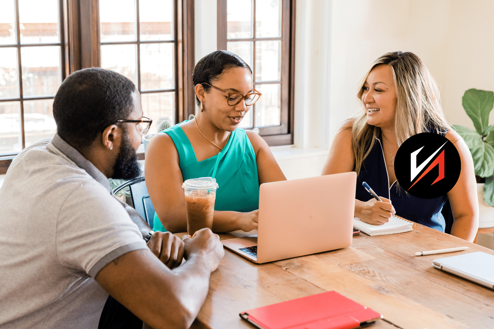 Three coworkers collaborating at laptop in bright office