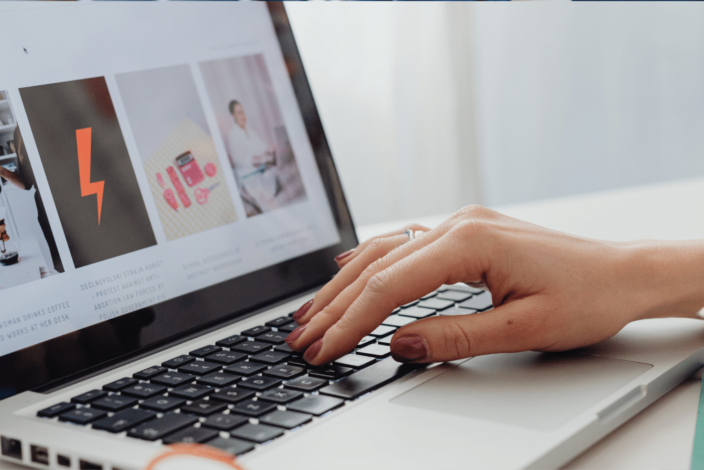 Hand typing on laptop browsing website